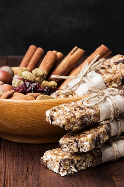 Barritas de cereales con diferentes frutos secos y muesli y tazón de ingredientes