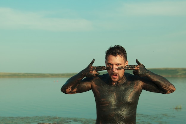 Barro terapéutico para el cuerpo baños de barro en el lago un hombre se unta con arcilla