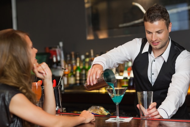 Bartender bonito que serve cocktail a mulher atraente