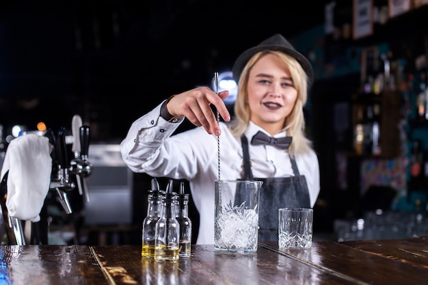 Bartender chica encantadora hace un espectáculo creando un cóctel detrás de la barra