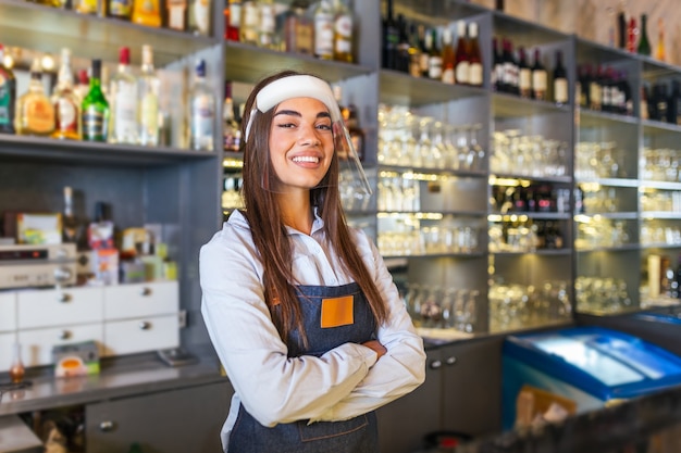 Bartender em pé no balcão, usando protetor facial