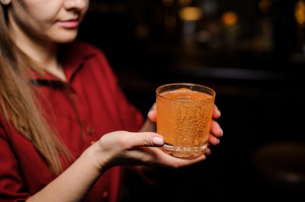 Bartender girl holding cocktail en el vaso decorado