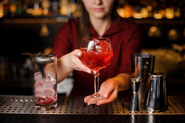 Bartender girl sosteniendo en las manos una copa de cóctel rojo