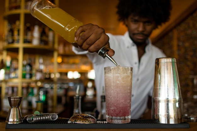 Bartender latino con el cabello rizado terminando un cóctel