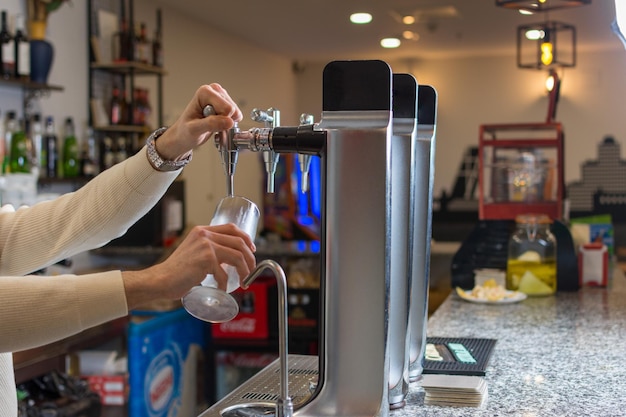 Bartender mit der Hand am Bierhahn, der ein Bier in ein Glas gießt, das in einer Bar oder einem Pub serviert wird