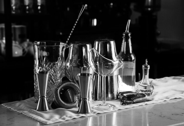 Barzubehör für die Zubereitung von Cocktails an der Bar, dahinter befindet sich ein Regal mit Likören und starkem Alkohol. Gemischte Medien