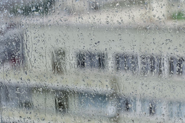 Foto basándose en el fondo de una ventana mojada con vetas de lluvia.