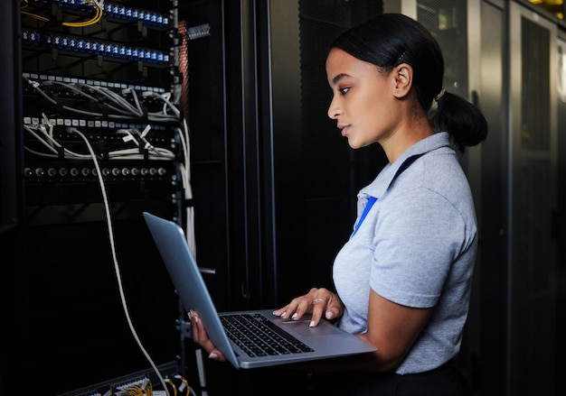 Base de datos de computadora portátil de ingeniero y mujer en la sala de servidores para actualización o mantenimiento de software por la noche Codificador de ciberseguridad computación en la nube y programadora con computadora para redes en el centro de datos