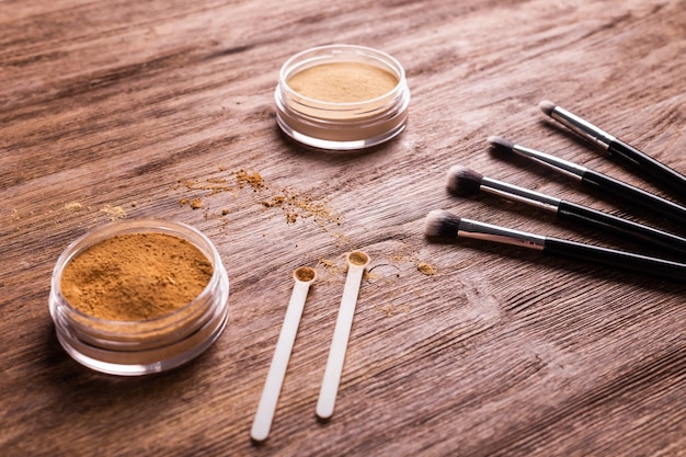 Base de maquillaje en polvo mineral con pinceles sobre fondo de madera, belleza ecológica y orgánica