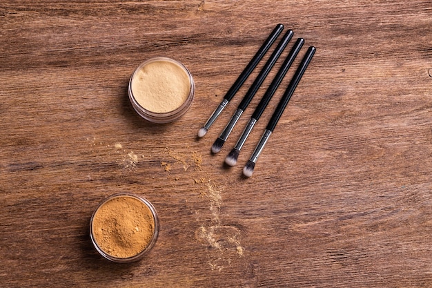 Base de maquillaje en polvo mineral con pinceles sobre un fondo de madera con espacio de copia ecológico y