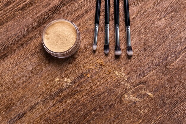 Base de maquillaje en polvo mineral con pinceles sobre un fondo de madera con espacio de copia ecológico y