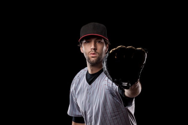 Baseballspieler, der einen Ball auf einem schwarzen Hintergrund fängt. Studioaufnahme.