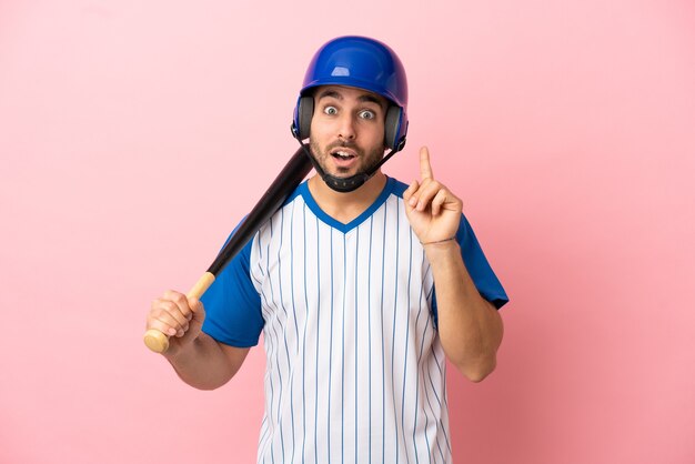 Baseballspieler mit Helm und Schläger einzeln auf rosa Hintergrund, der die Lösung realisieren möchte, während er einen Finger hochhebt