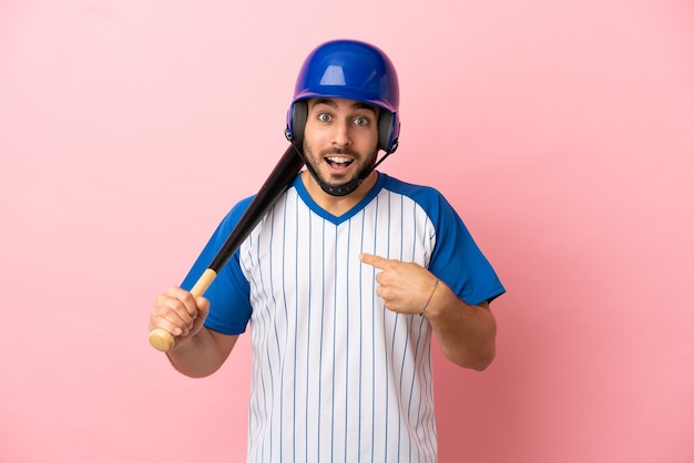 Baseballspieler mit Helm und Schläger einzeln auf rosafarbenem Hintergrund mit überraschendem Gesichtsausdruck