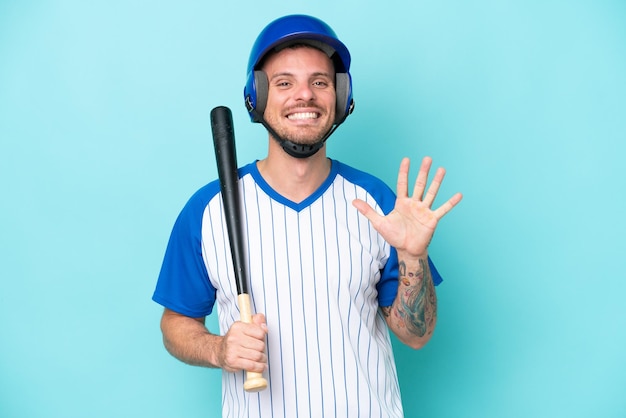 Baseballspieler mit Helm und Schläger isoliert auf blauem Hintergrund, der fünf mit den Fingern zählt