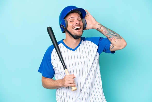 Baseballspieler mit Helm und Schläger isoliert auf blauem Hintergrund, der viel lächelt