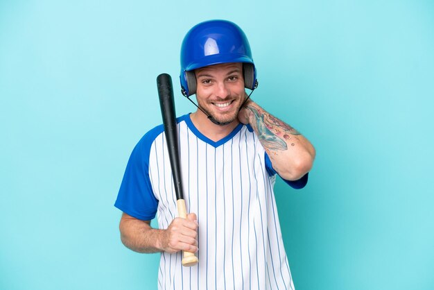 Baseballspieler mit Helm und Schläger isoliert auf blauem Hintergrund lachend