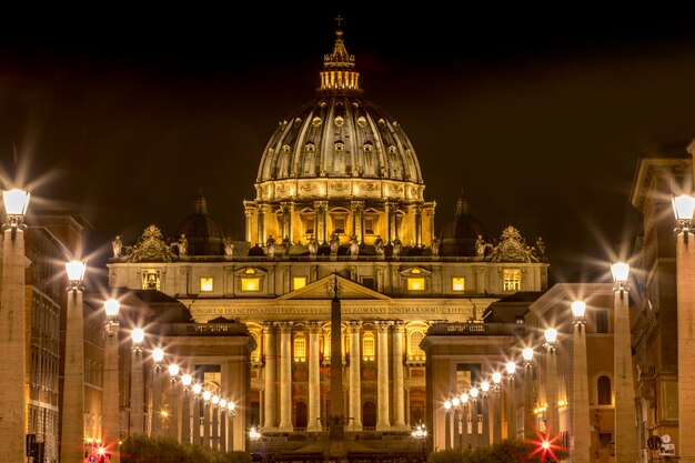 Foto basílica de são pedro iluminada contra o céu na cidade à noite