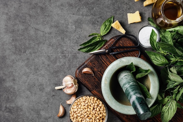 Basilikum-Pesto mit Zutat für die Saucenzubereitung auf dem Küchentisch Draufsicht Marmormörser und Gewürze zum Kochen