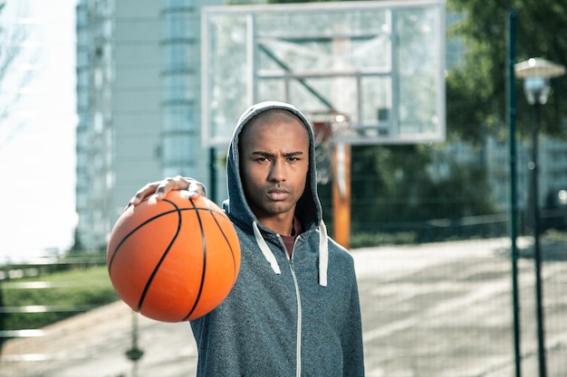 Basketball Spiel. Netter gutaussehender Mann, der Sie beim Basketballspielen ansieht