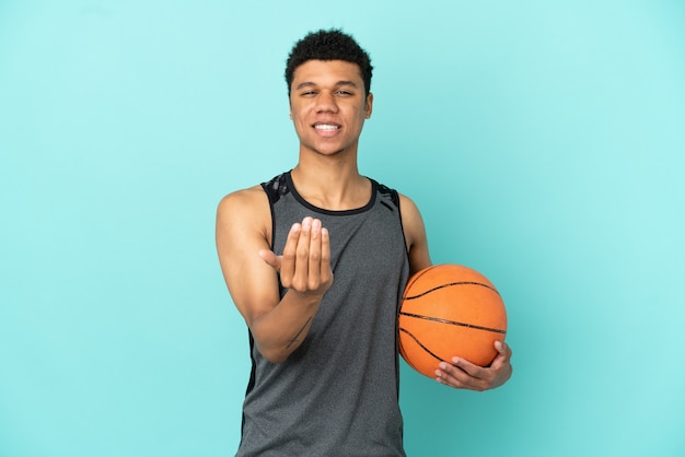 Basketball-Spieler African American Mann isoliert auf blauem Hintergrund, der einlädt, mit der Hand zu kommen. Schön, dass du gekommen bist