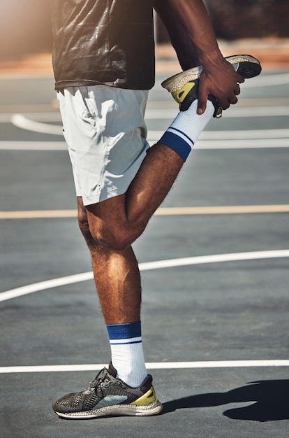 Basketballplatz Mann und Strecken der Beine im Freien für Übung Muskelenergie und gesundes Training des Sportspiels Nahaufnahme Basketballspieler starten Körper Aufwärmen Füße Gleichgewicht und Energie im Wettbewerb