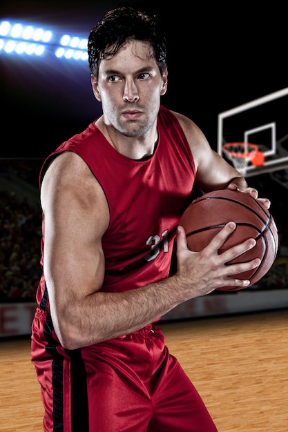 Basketballspieler mit einem Ball in den Händen und einer roten Uniform. Fotostudio.