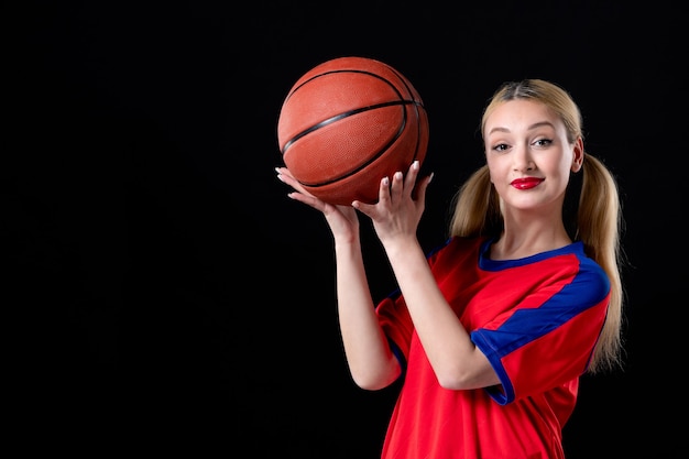 Basketballspielerin in Sportkleidung mit Ball auf schwarzem Hintergrund Übungsspiel Athlet