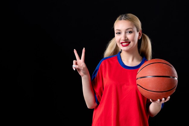 Basketballspielerin in Sportkleidung mit Ball auf schwarzem Schreibtisch Übungsspiel Athlet