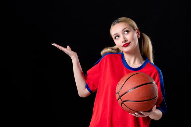 Basketballspielerin in Sportkleidung mit Ball auf schwarzem Schreibtischspiel Athlet spielen