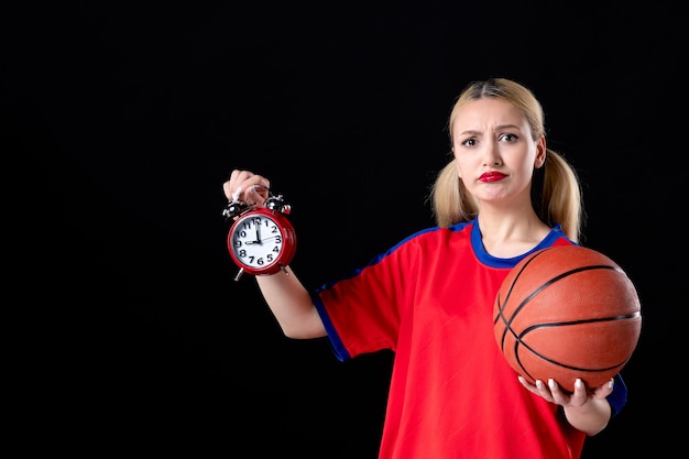 Basketballspielerin mit Ball und Uhren auf schwarzem Hintergrund Athlet Spielaktion
