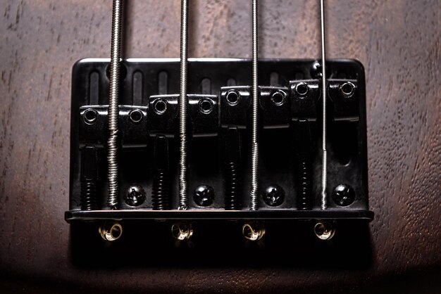 Bass-E-Gitarre mit vier Saiten Nahaufnahme Detail des beliebten Rockmusikinstruments Vintage-Foto der Metallbrücke der braunen Bassgitarre