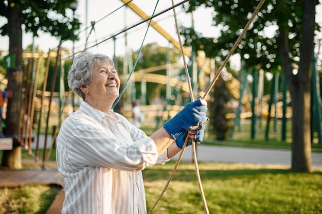 Bastante abuela escalada en cuerdas en el parque de verano