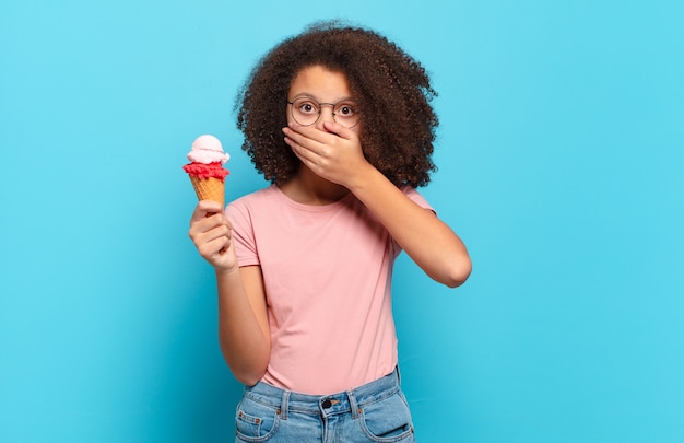 Bastante adolescente afro cubriendo la boca con las manos con un sorprendido