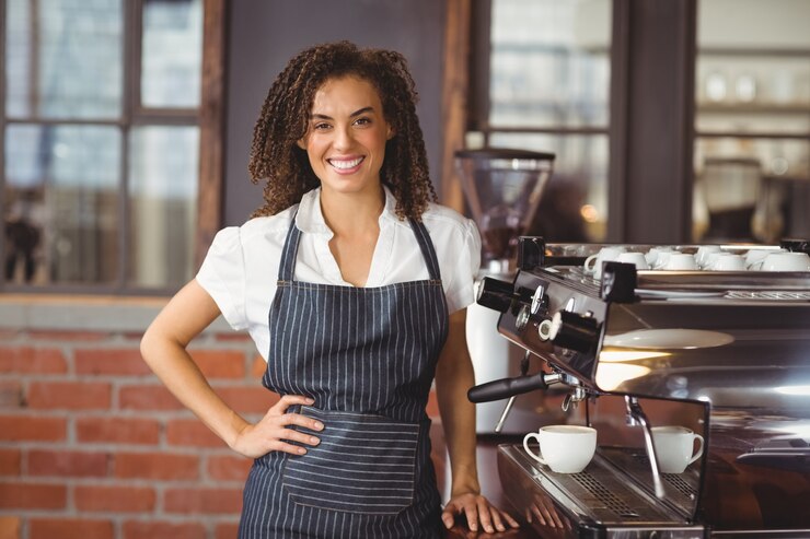 Foto bastante barista sonriendo al lado de la máquina de café