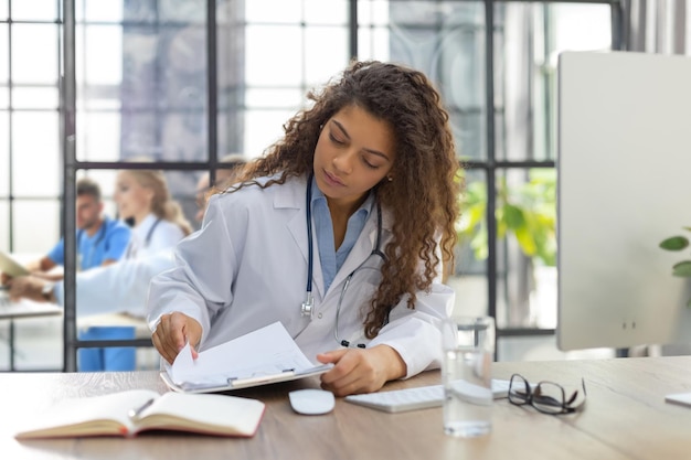 Foto bastante doctora terapeuta en la consulta los colegas están en el fondo