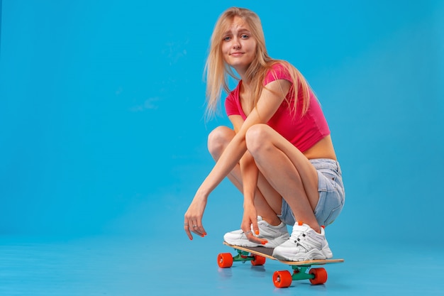 Bastante feliz mujer vestida casualmente se sienta en su patineta