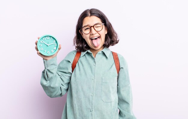 Bastante joven con actitud alegre y rebelde, bromeando y sacando la lengua. concepto de reloj despertador