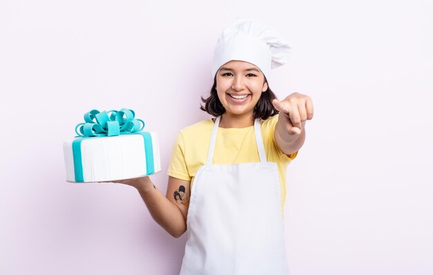 Bastante joven apuntando a la cámara eligiéndote. chef cocinando un pastel