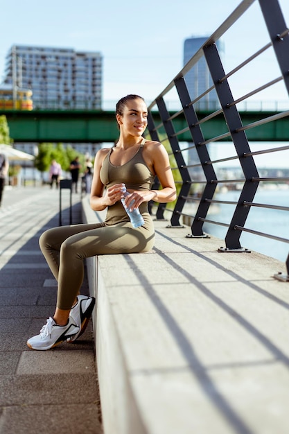 Bastante joven con auriculares se toma un descanso después de correr en zona urbana