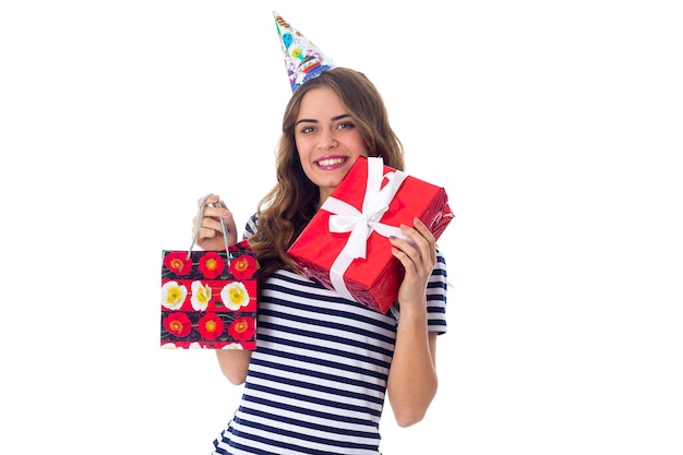 Bastante joven en camiseta pelada y gorra de celebración sosteniendo regalos sobre fondo blanco en el estudio