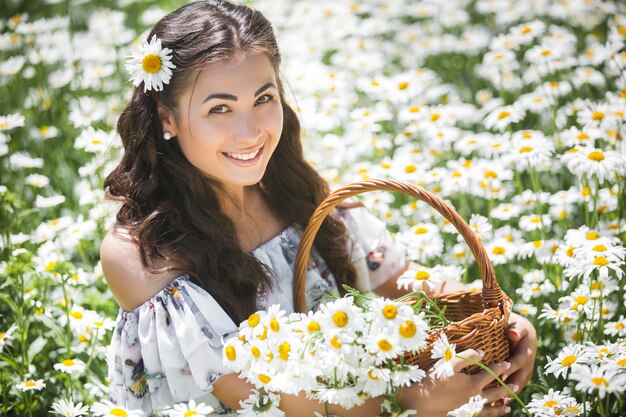 Bastante joven en el campo de manzanilla. Hermosa chica con flores