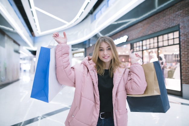 Foto bastante joven con una chaqueta rosa en el centro comercial