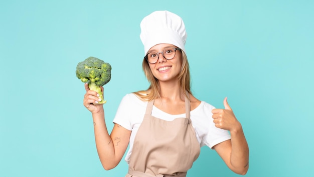 Bastante joven chef rubia sosteniendo un brócoli