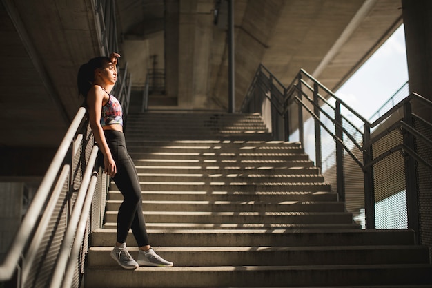 Bastante joven corredor femenino descansando en las escaleras