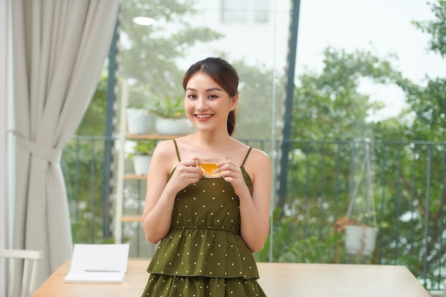 Bastante joven disfrutando del primer té de la mañana junto a la ventana