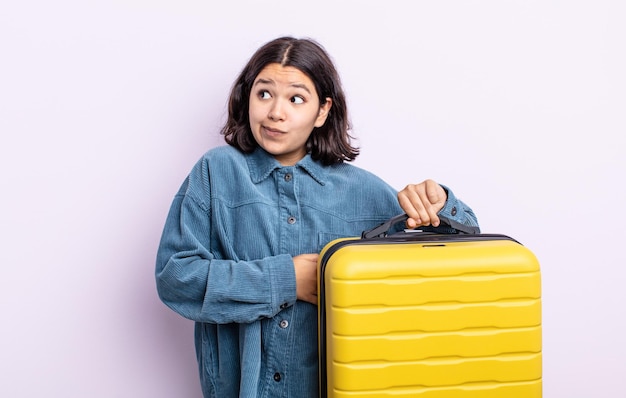 Bastante joven encogiéndose de hombros, sintiéndose confusa e insegura. concepto de estuche de viaje