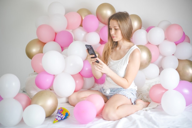 Bastante joven escribiendo en el teléfono inteligente en su dormitorio.