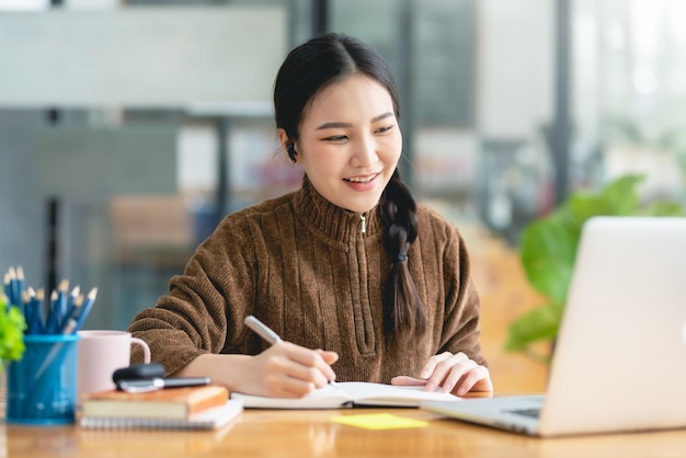 Bastante joven estudiante asiática que estudia en línea en una computadora portátil