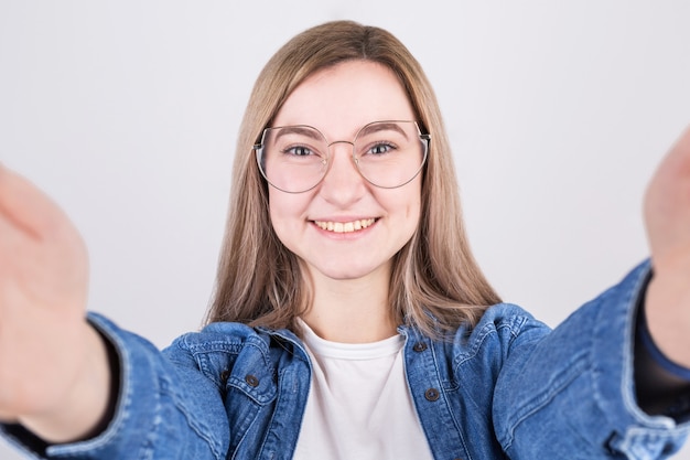 Bastante joven con gran sonrisa divirtiéndose tomando selfie alegre luz en gris